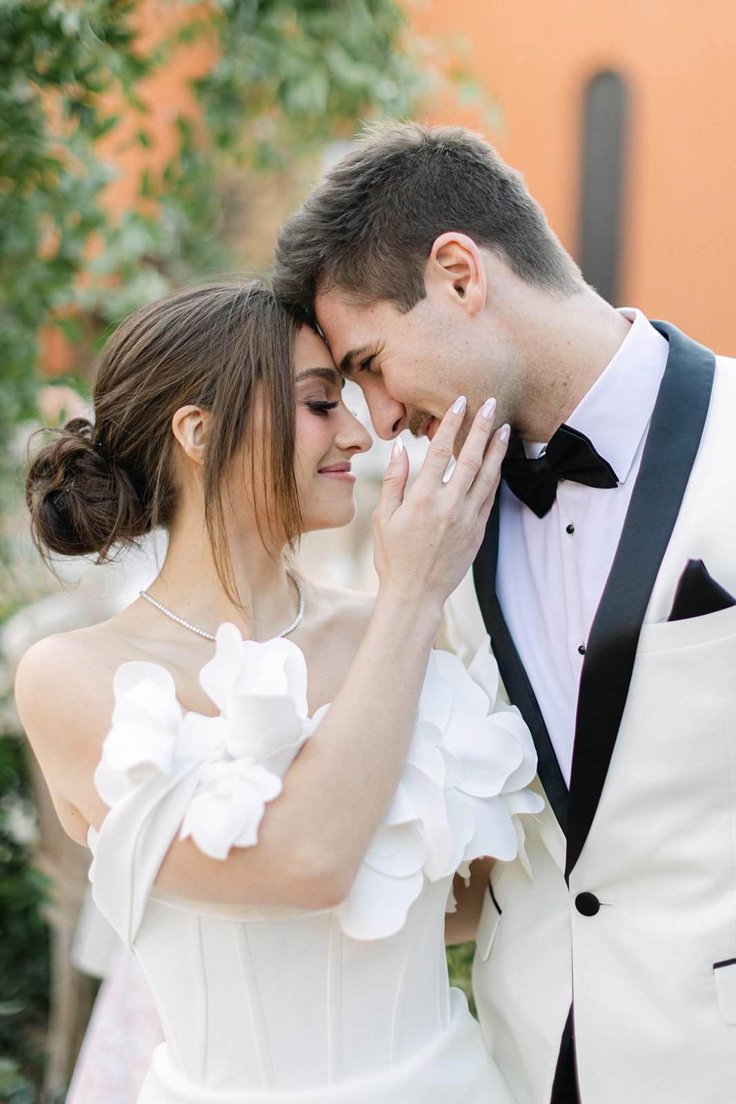 A groom wearing a black tuxedo by Bravo Suit and Tux poses with his bride at Agave Estates in Houston TX