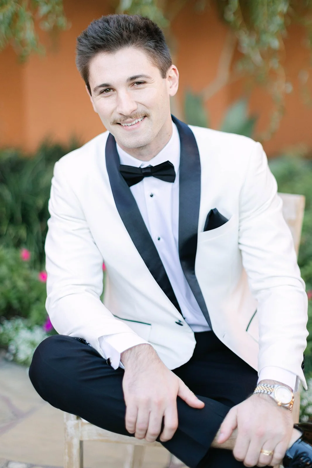 A groom smiling in a white tuxedo jacket and black pants by bravo Suit and Tux in Houston TX