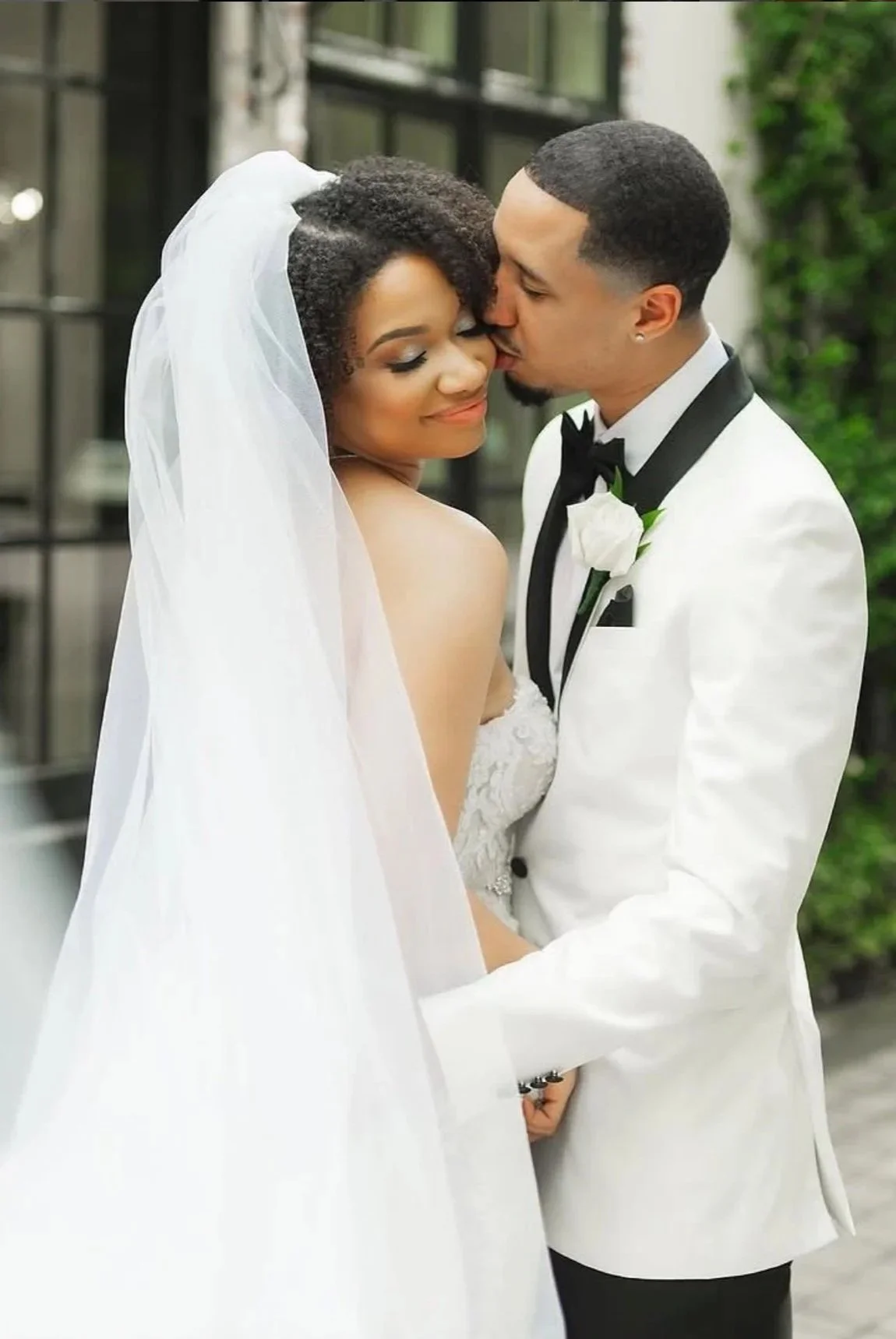 Groom wearing white tuxedo with bride.