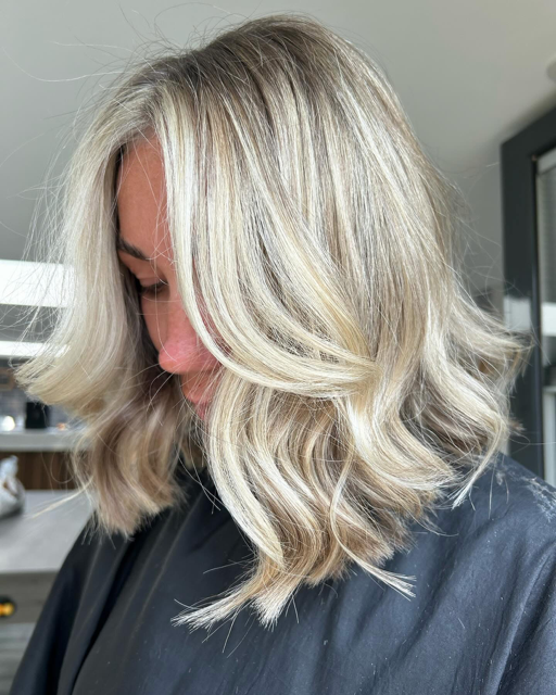 Close-up of a woman with shoulder-length, wavy blonde hair looking downward.
