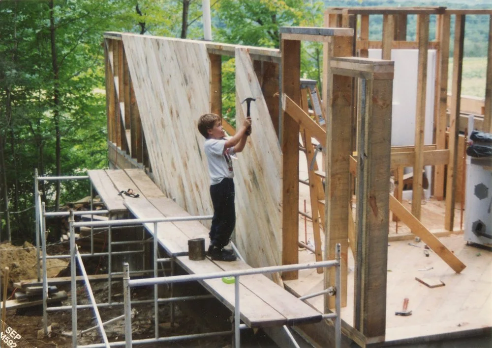 Ben, age 8, hammers pine sheathing onto the north wall of his family’s Monroe home.