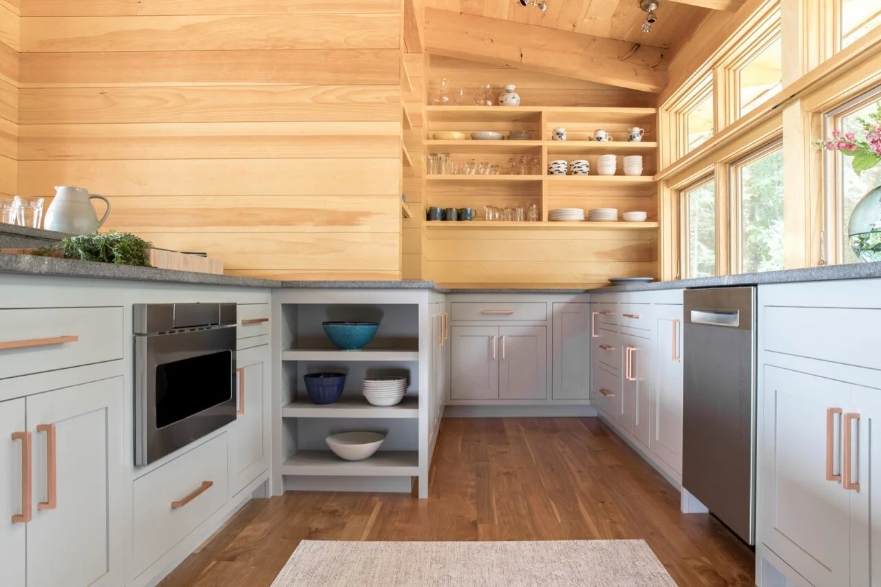 Modern kitchen with white cabinets, open shelving, granite countertops, and large windows letting in natural light