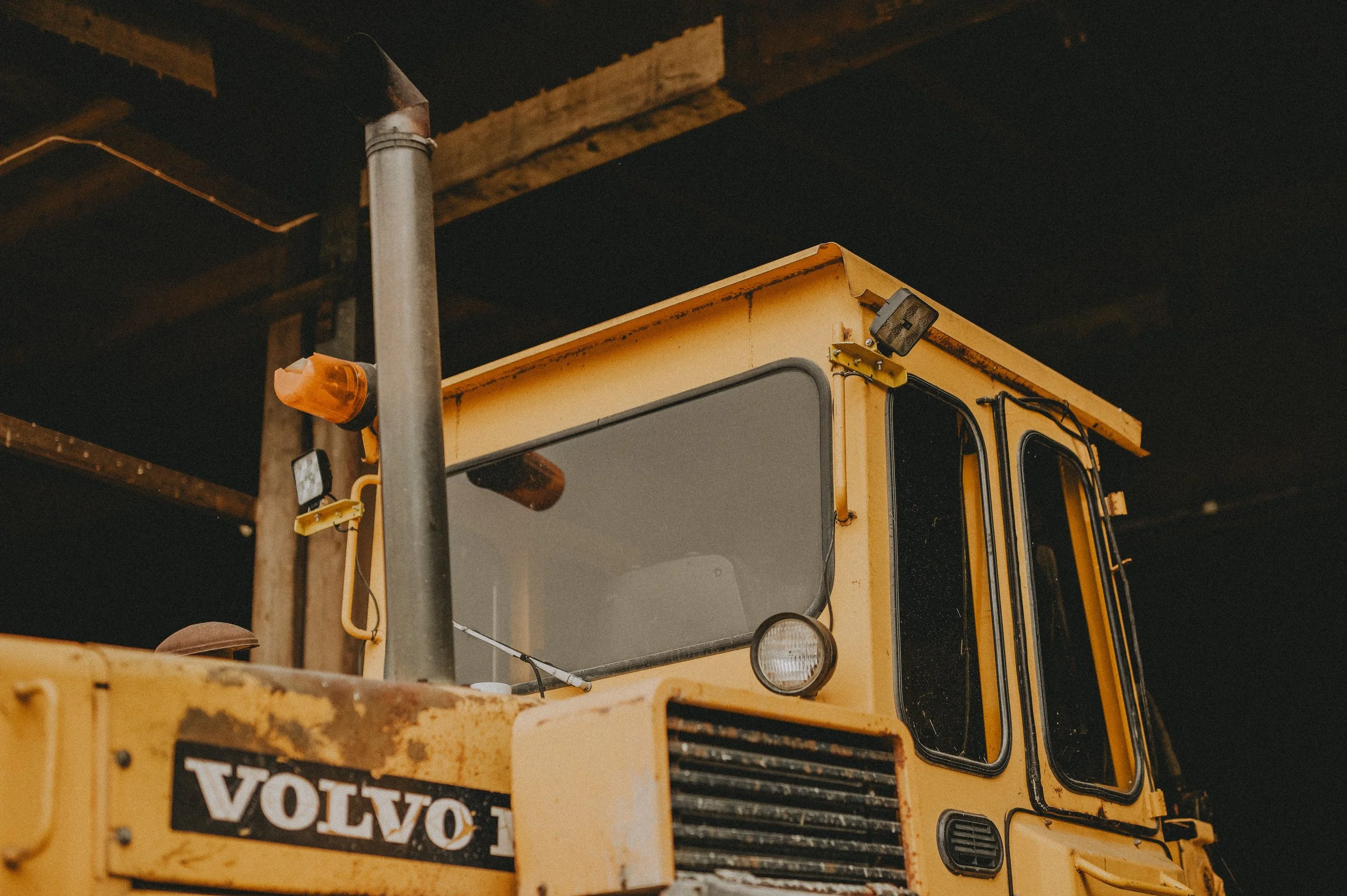 En gul Volvo grävmaskin under ett tak