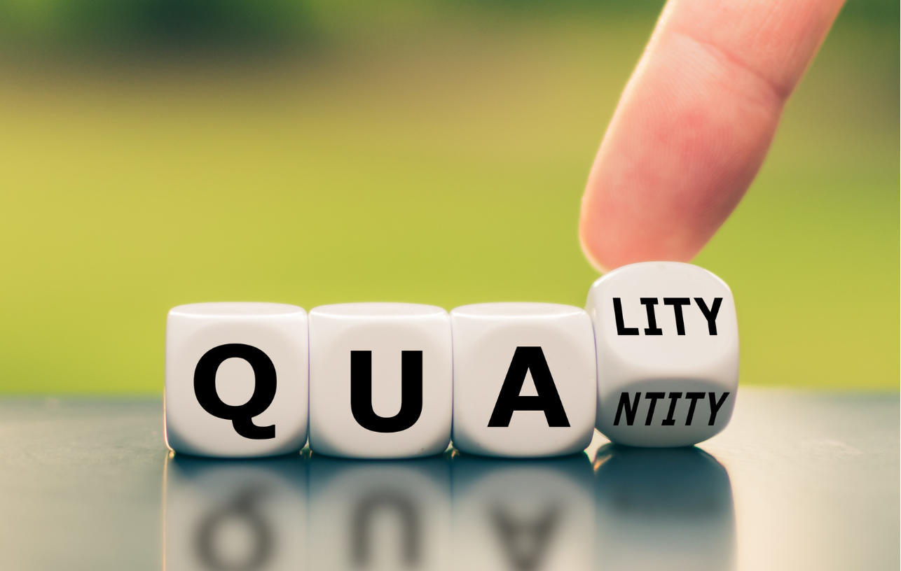 Dice spelling 'QUALITY,' with the last die being squeezed to show the letter 'LITY'.