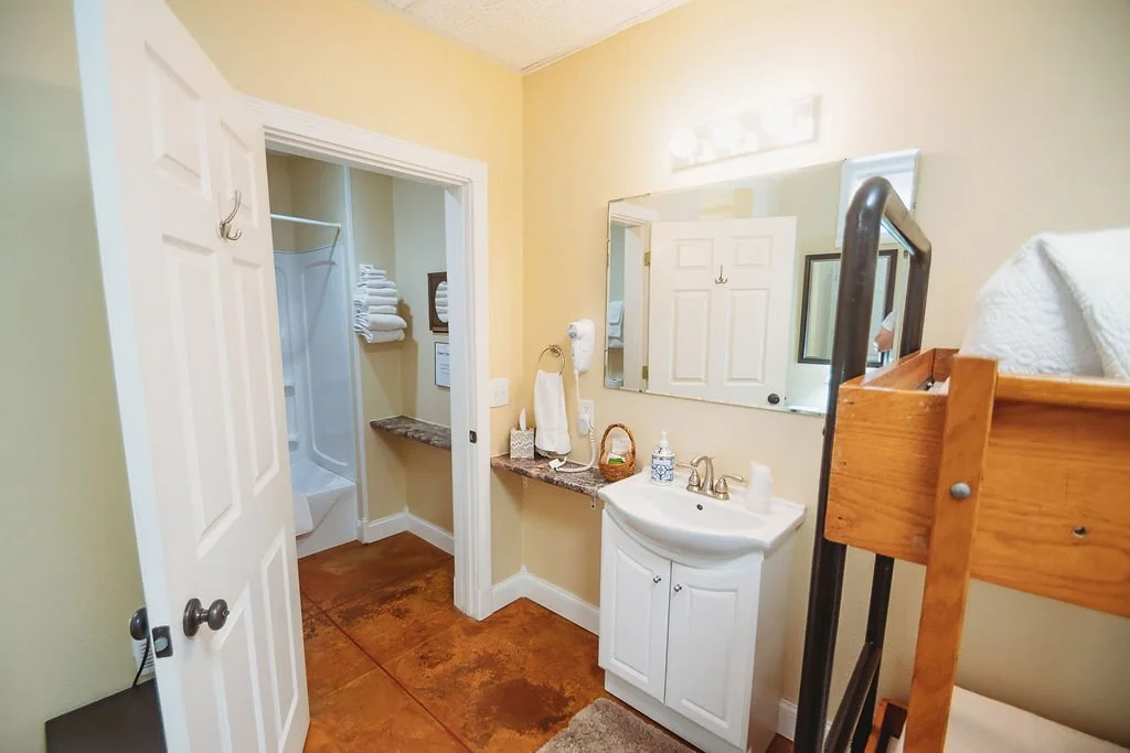 Bathroom with a small sink, mirror, bunk beds, and a walk-in shower