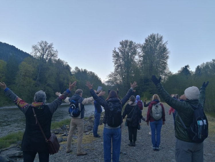 Participants moving together outdoors with their arms raised