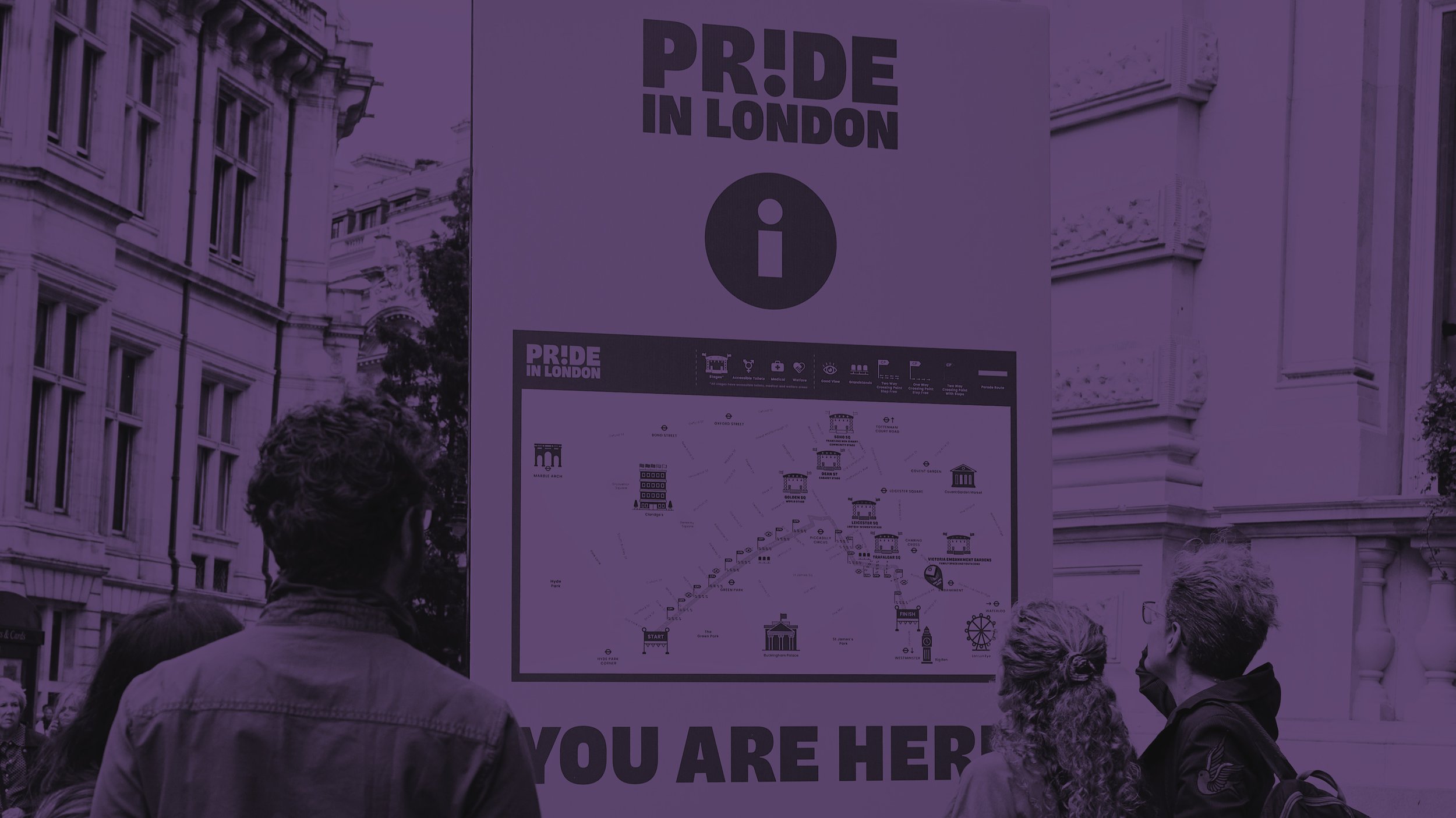 A purple-tinted photo of people looking at a large "Pride in London" information board. The board features a detailed map of the event route and stages, with the text "YOU ARE HERE" at the bottom.