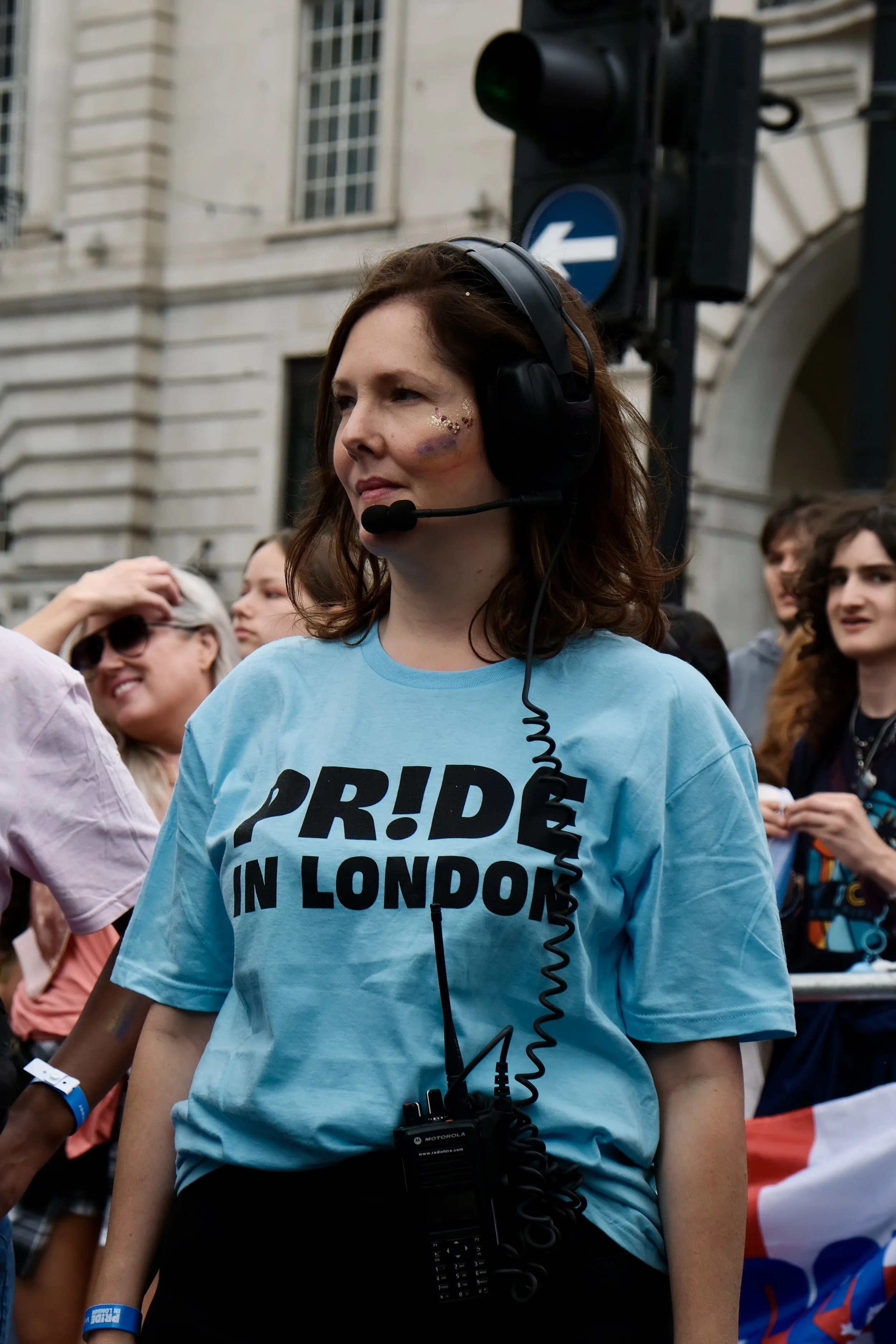 A volunteer Pride in London steward managing pedestrian traffic in Piccadlly Circus