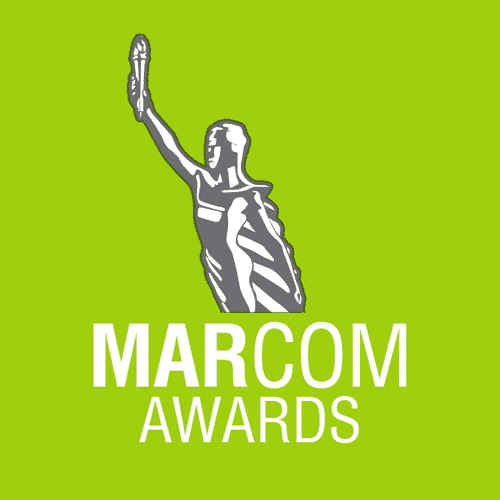 Illustration of the Statue of Liberty raising its right hand against a green background with the text "MARCOM AWARDS" below.