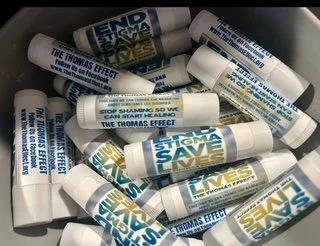 Collection of lip balm tubes with text promoting 'The Thomas Effect' and 'Big Save' on white labels.