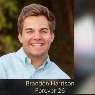 Close-up of a young man smiling outdoors, wearing a light blue shirt, with text overlay showing his name, Brandon Harrison, and age, 26.