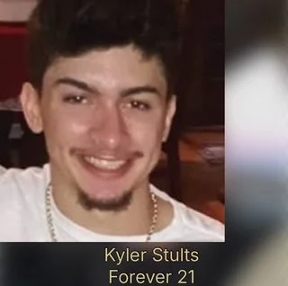 Young man with dark hair and a beard smiling, wearing a white shirt and a gold chain, with text overlay reading 'Kyler Stults Forever 21'.
