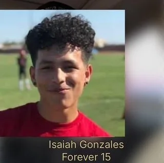 Young man with curly hair smiling outdoors in a red shirt, with text overlay that says 'Isaiah Gonzales Forever 15'.