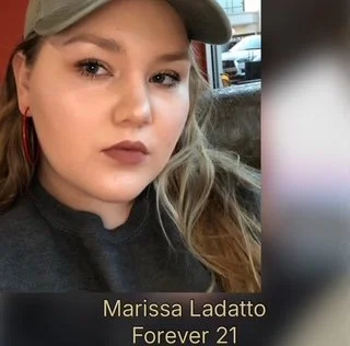 Close-up of a young woman with light brown hair, wearing a gray cap and dark lipstick, sitting in a car. Text overlay says 'Marissa Ladatto Forever 21'.