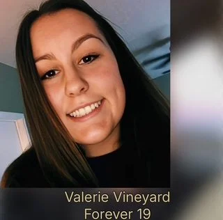 Close-up of a young woman with brown hair and a wide smile, with a caption that says 'Valerie Vineyard Forever 19'.