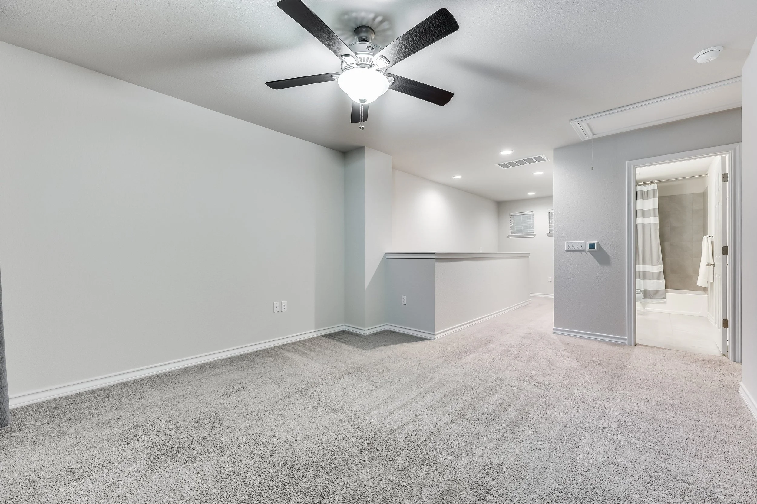 5216 Golden Canary Lane Austin, TX 78723. Empty carpeted room with a ceiling fan, white walls, and open doorway leading to bathroom with a shower curtain.