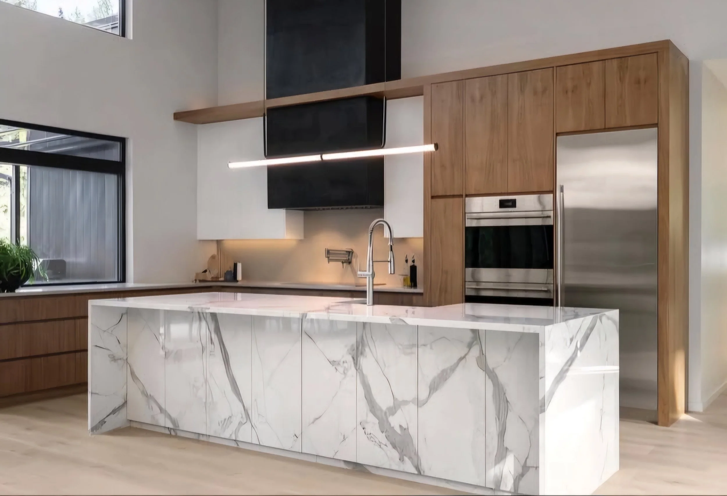 Modern kitchen with a marble island, stainless steel appliances, wooden cabinets, and large windows.