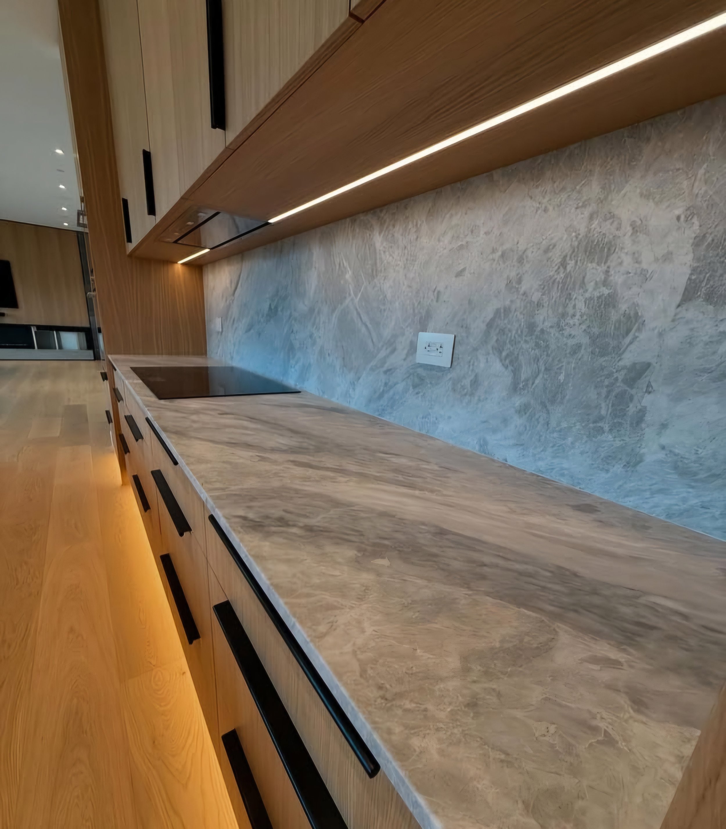 Modern kitchen cabinet with a marble countertop, wooden upper cabinets, and a marble backsplash.