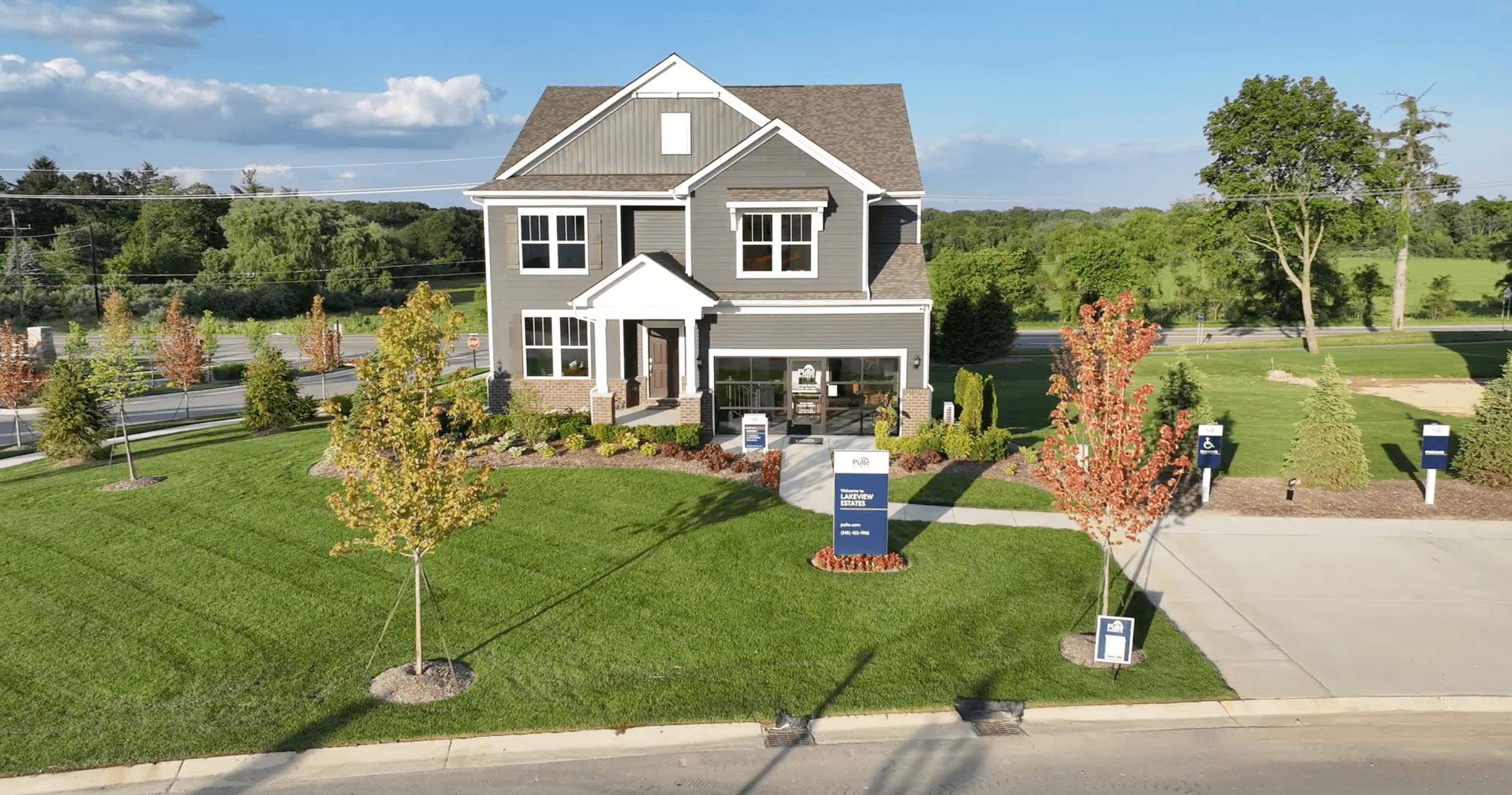 A modern two-story house with gray siding and newly installed sod curving around landscaped walkway.