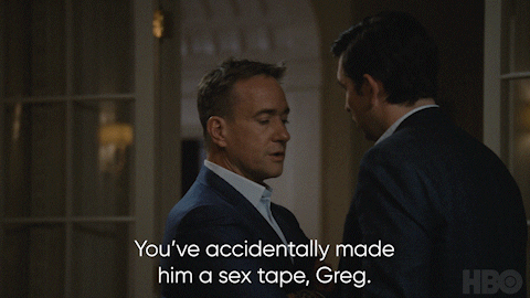 Two men in suits having a serious conversation indoors with a caption that says, "You've accidentally made him a sex tape, Greg."