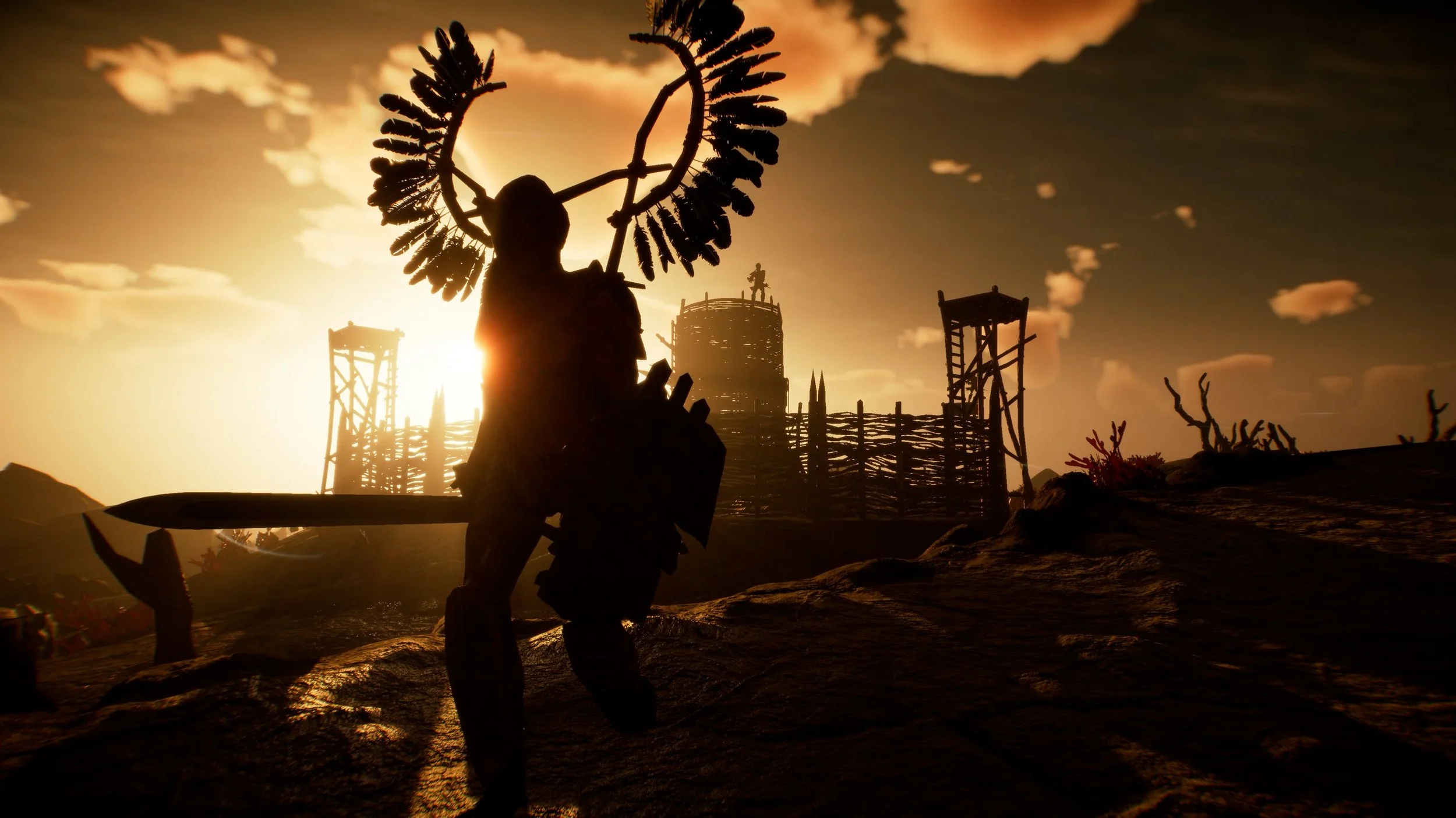 Silhouette of a warrior with a spear and a shield, wearing a headdress with feathers, standing on rough terrain during sunset or sunrise. In the background, there is a wooden fort with watchtowers and a figure on top, against a sky with clouds and a warm glow.