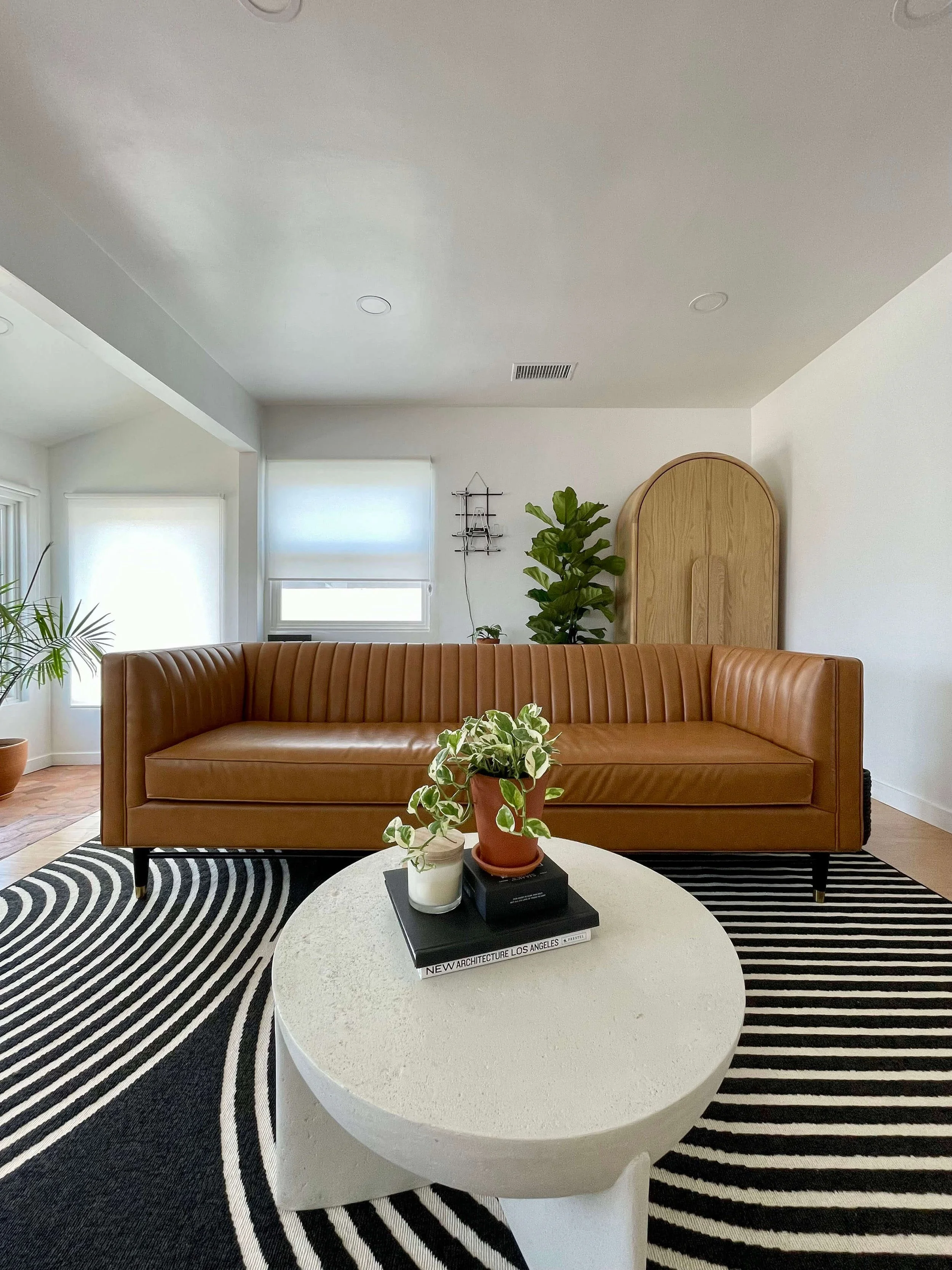 Contemporary modern interior design at 6605 & 6603 4th Ave in Hyde Park with brown leather couch, ivory coffee table and linear pattern black and white rug.