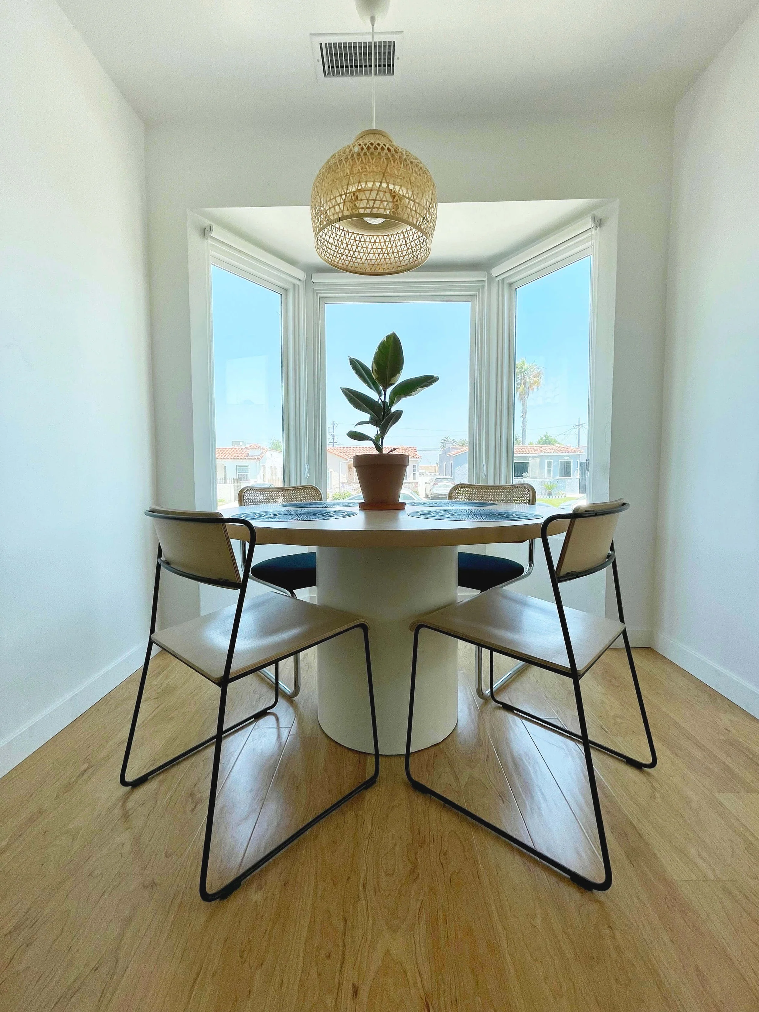Sunlight dining room at 6605 & 6603 4th Ave in Hyde Park featuring a round dining table, rod iron black chairs and a bright white bay window.