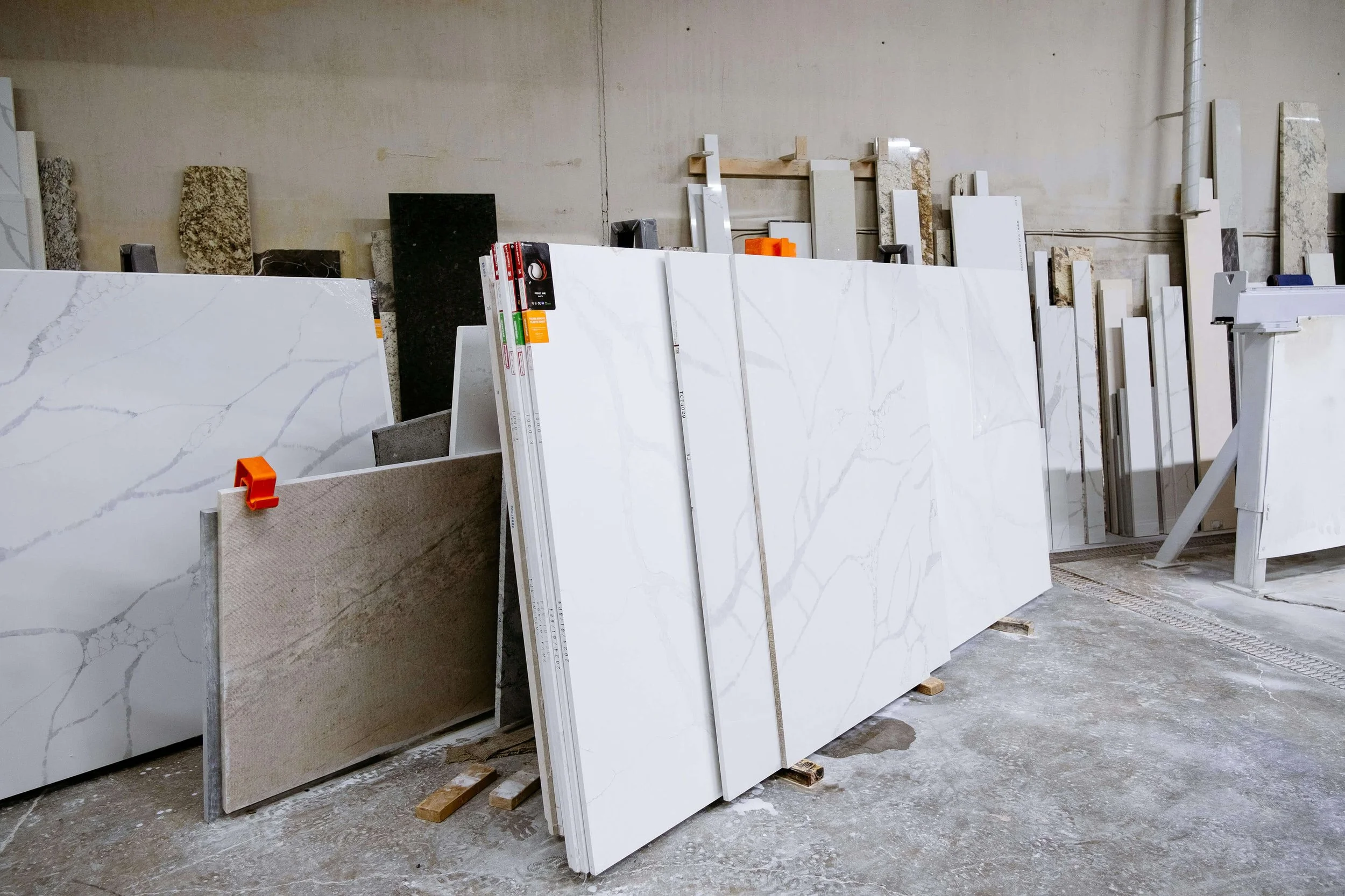 Large white marble tiles with gray veining arranged vertically on display racks in a warehouse.