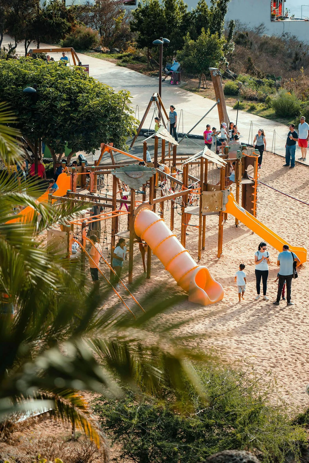 Southwest LA community park with children playing in the sand with lush greenery in the background.