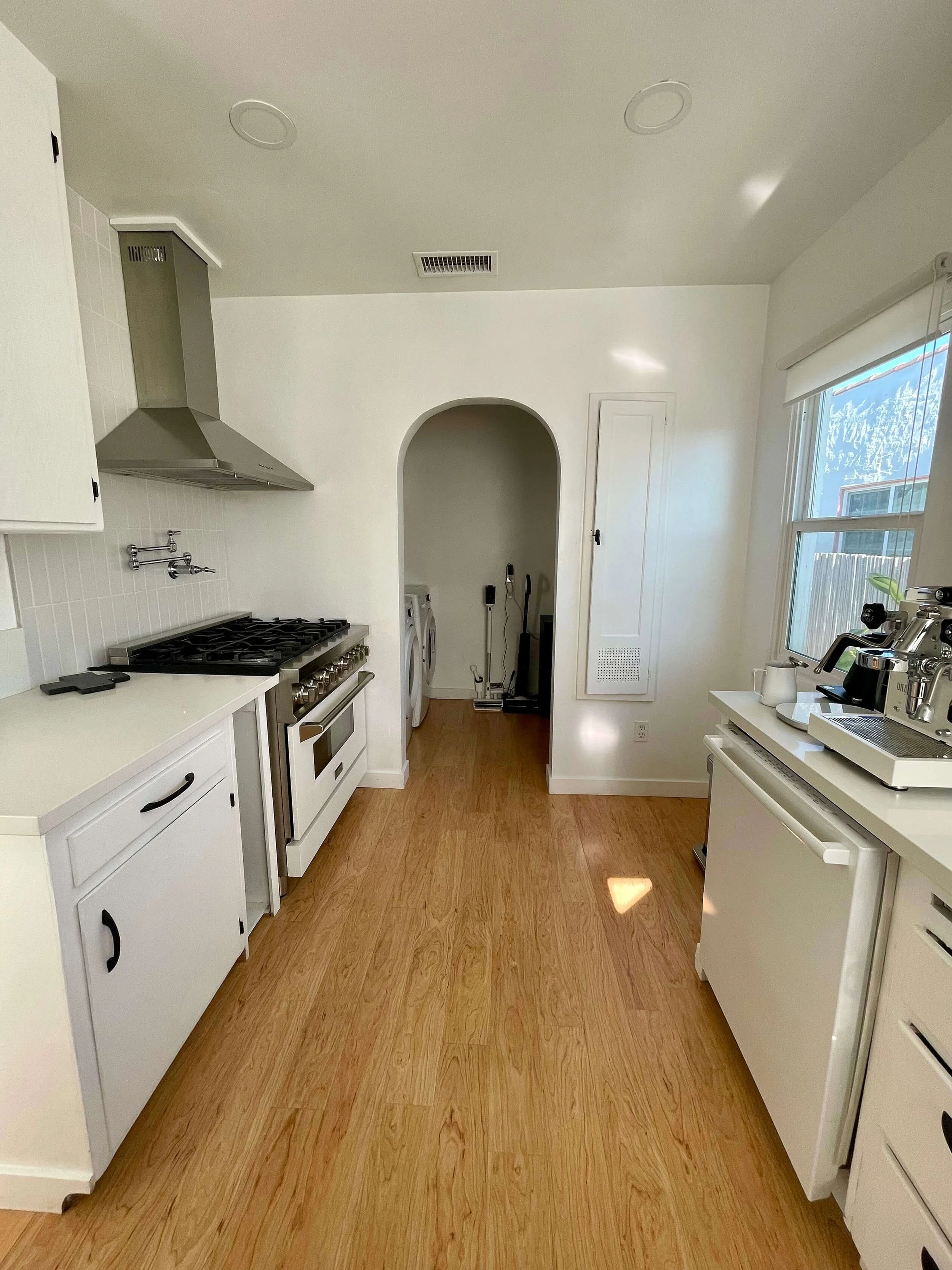 Newly renovated kitchen at 6605 & 6603 4th Ave in Hyde Park featuring an archway, stainless steel appliances, wood flooring and white cabinetry.