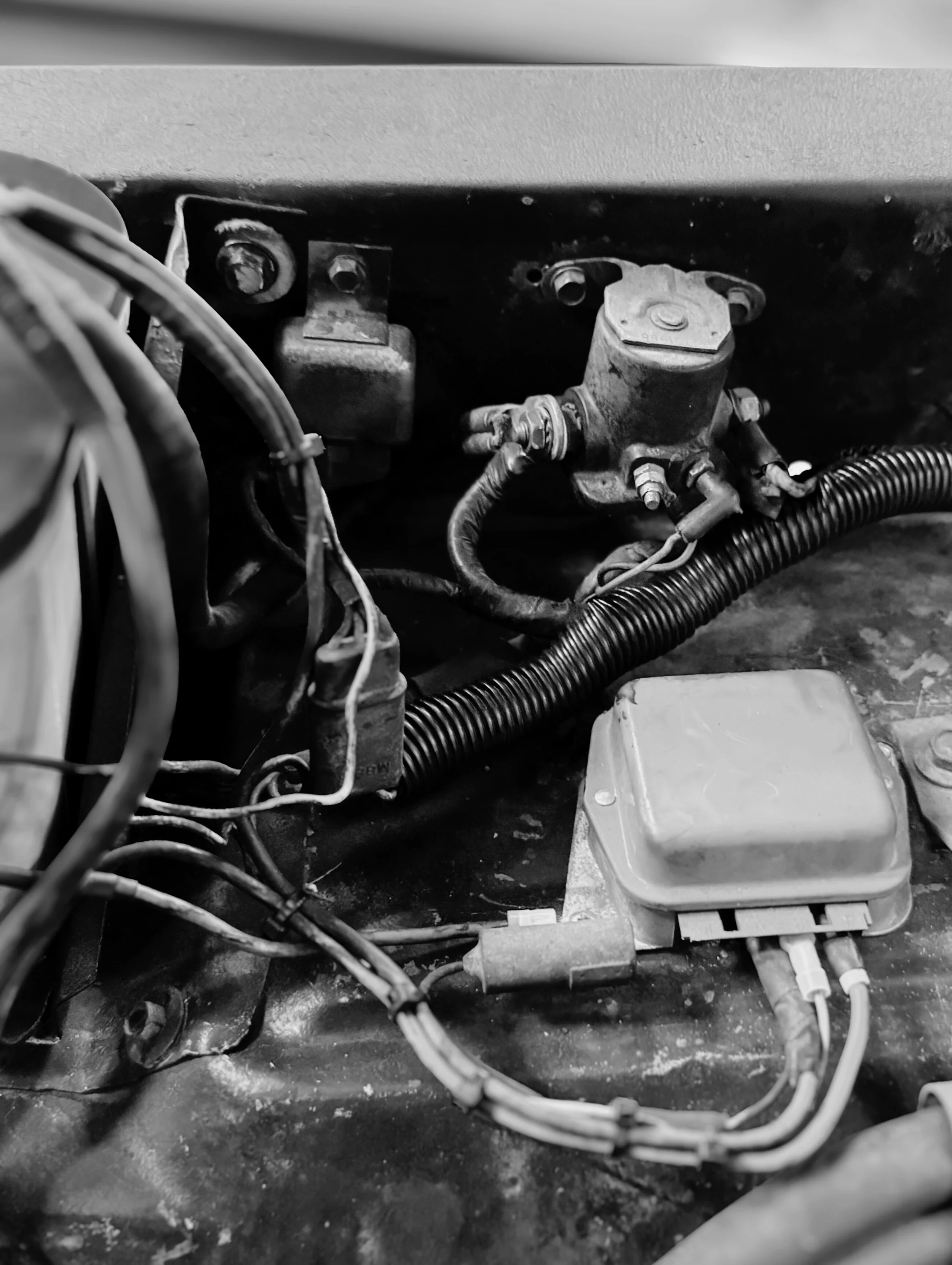Close-up of mechanical components and wiring inside a machine or vehicle, including metal parts, hoses, and electrical wiring.