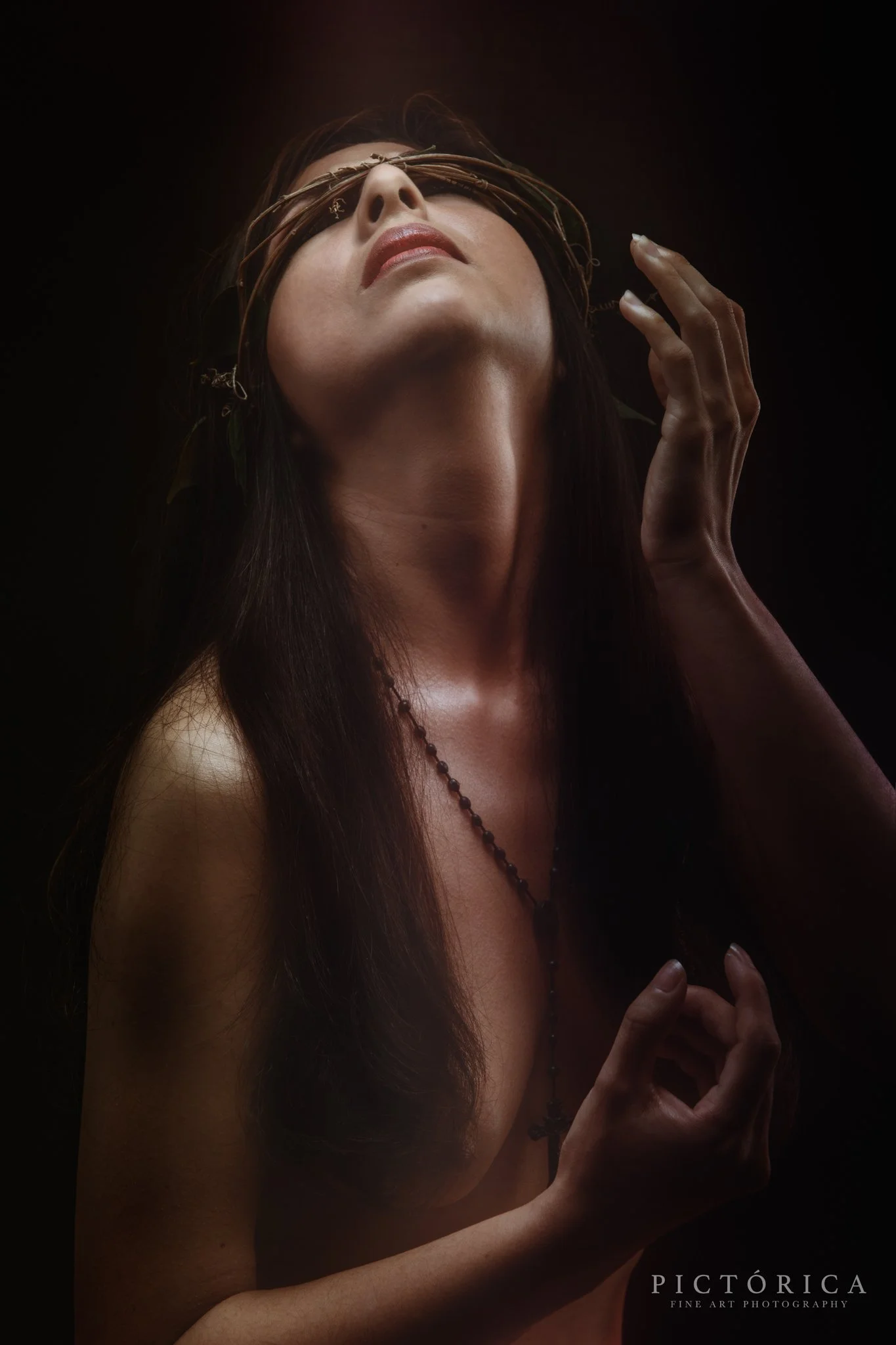 Retrato de una mujer con una corona de espinas en la cabeza, con los ojos vendados, en un fondo oscuro.