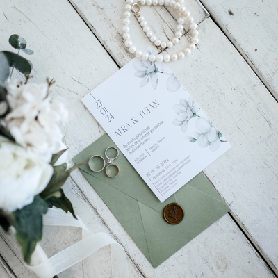 Elegant wedding invitation suite with green envelope and floral design details.