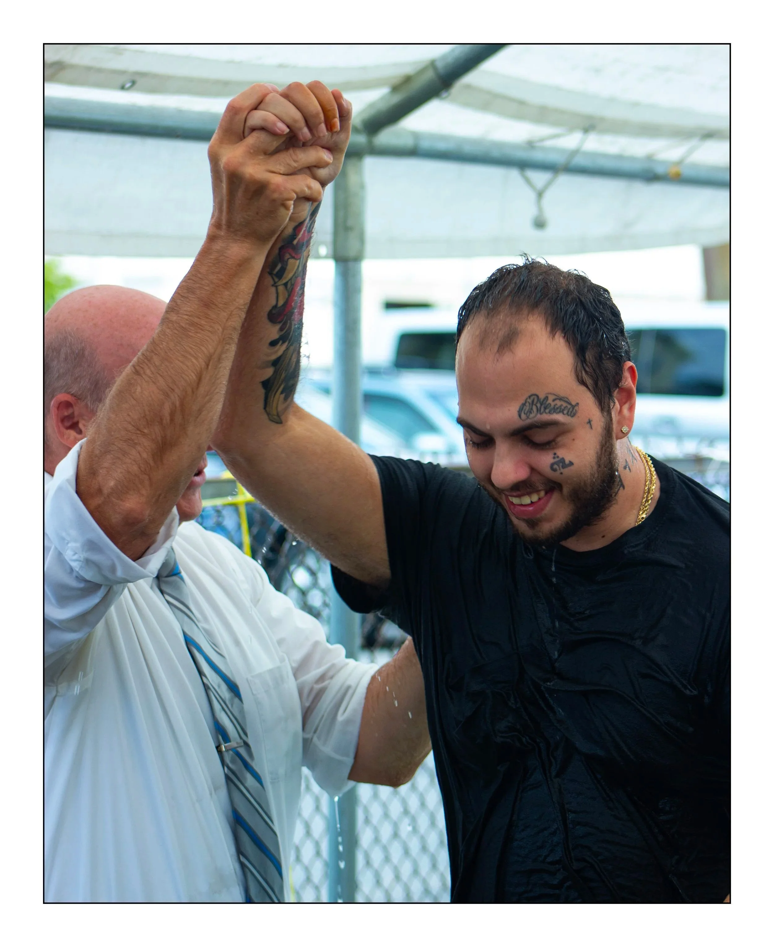 Pastor Kevin, holding up the hand of a Man who just got Baptized. A smile on his face.