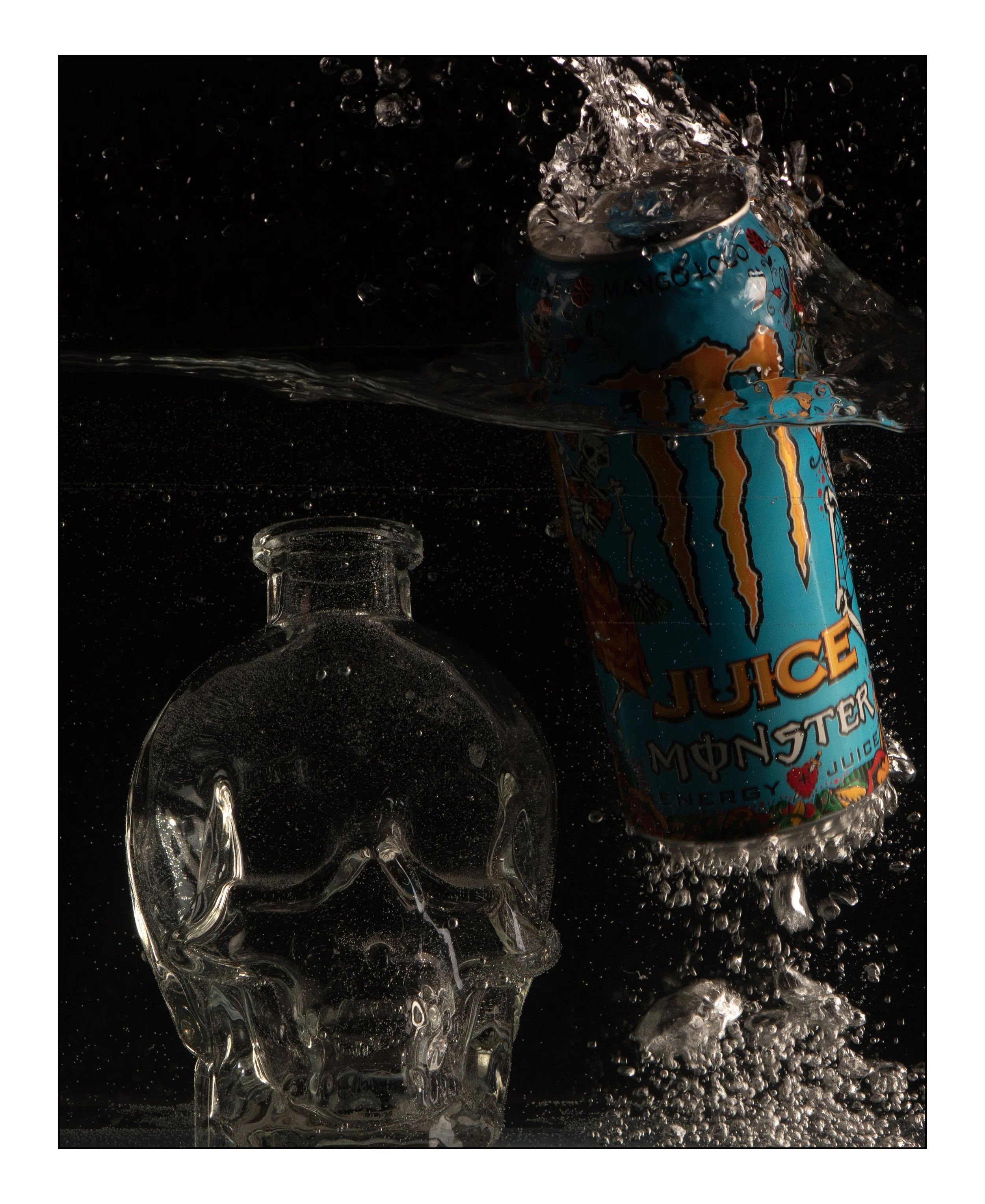 A can of Monster energy juice falling into water, creating a splash, next to an empty glass skull.