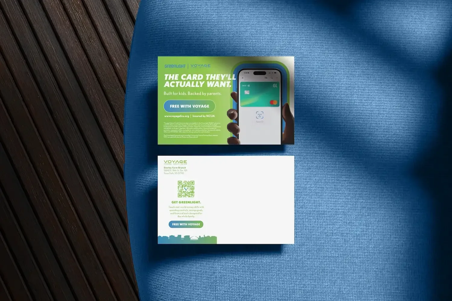 Voyage FCU Postcard reading "THE CARD THEY'LL ACTUALLY WANT," showing a hand holding an Iphone's apple pay with a Greenlight debit card.