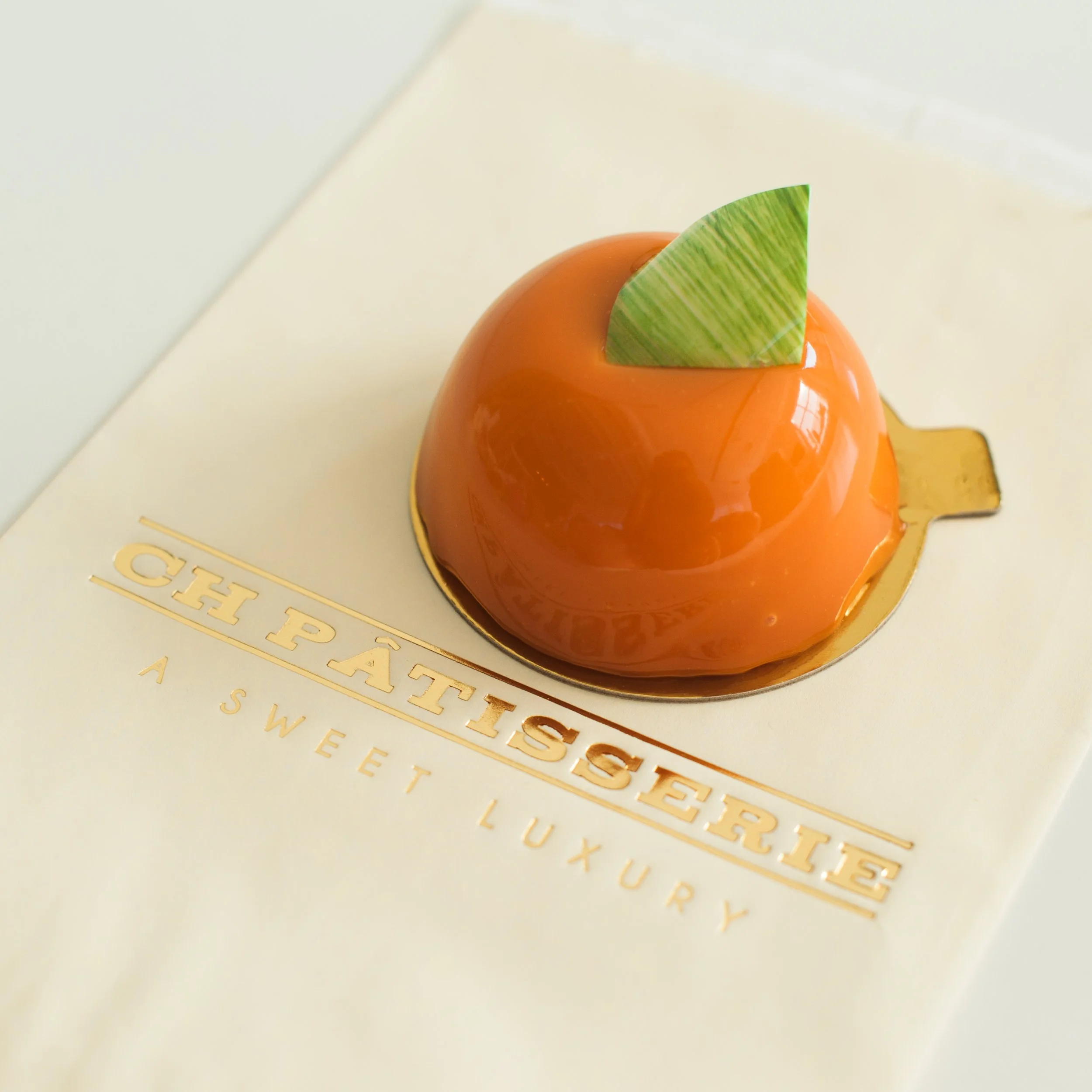 Close up of orange glossy pastry from CH Patisserie.