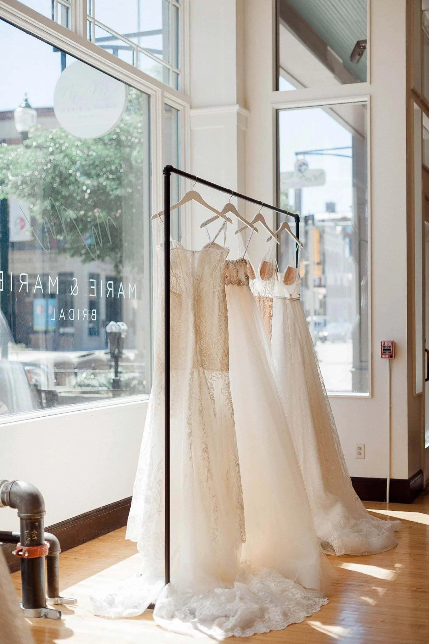 four wedding dresses hanging on a rack on display