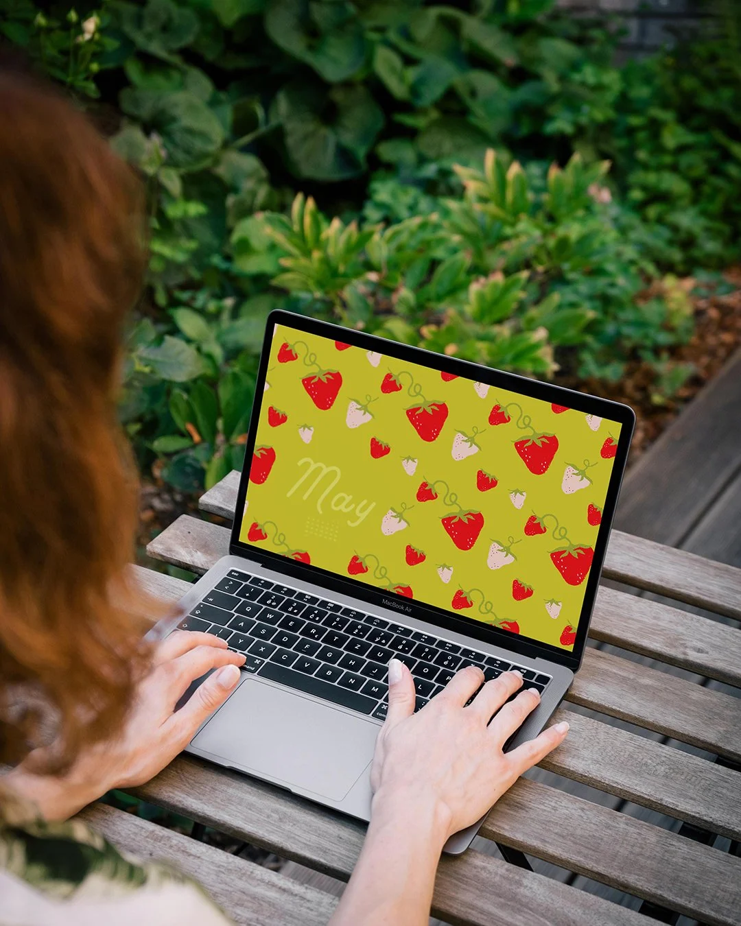 a laptop with red and pink strawberries and a may calendar