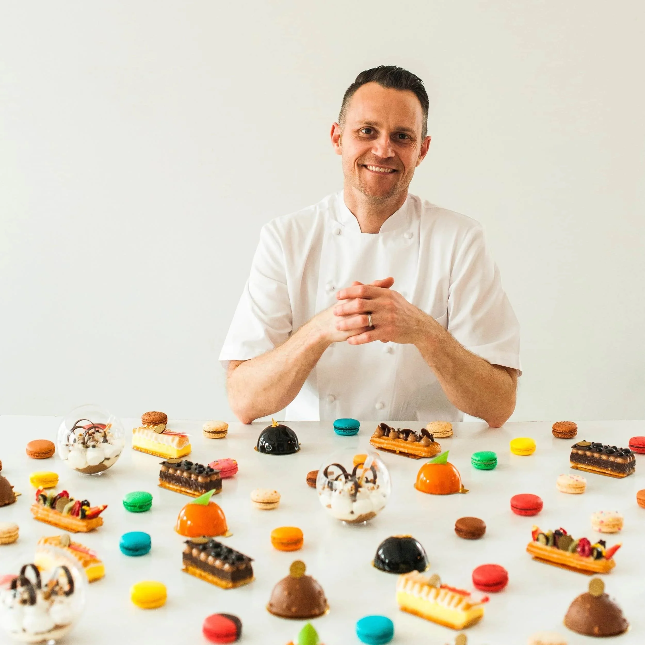 Pastry Chef Chris Hanmer with a table full of sweets and pastries