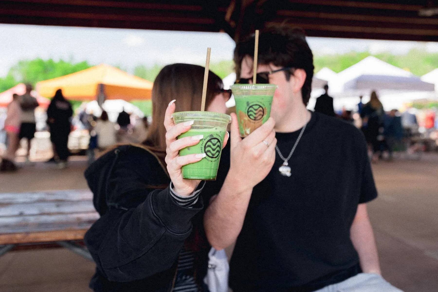 Couple holding out iced matcha.
