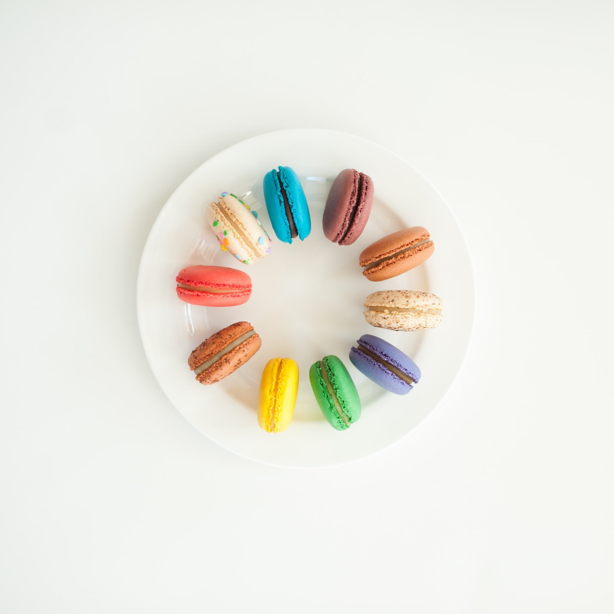 Different colored macarons on a white plate.