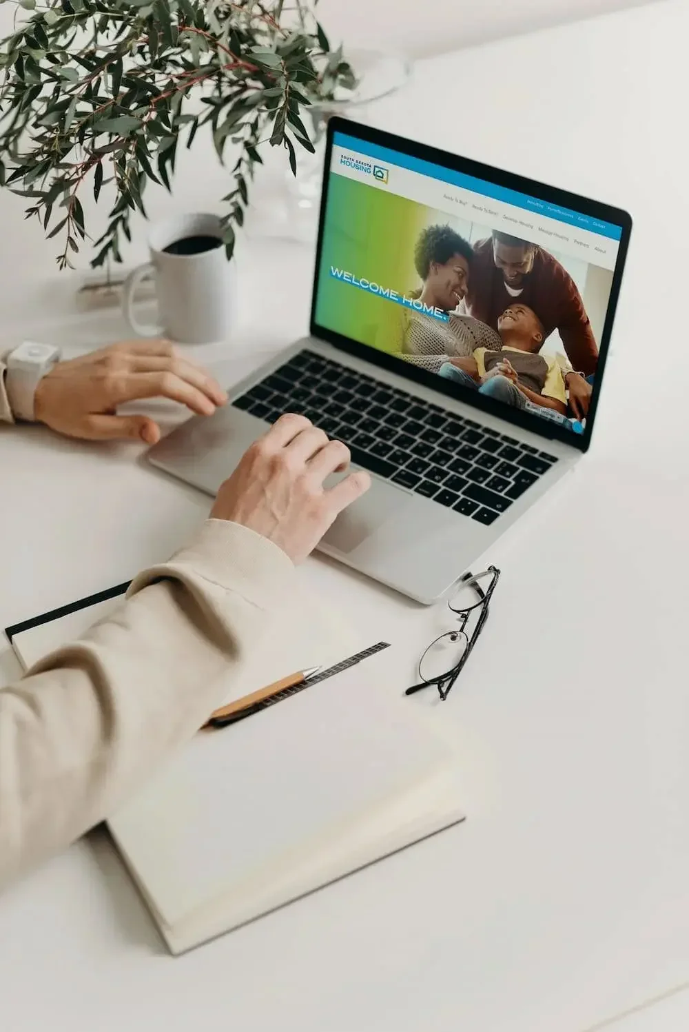 A male scrolling South Dakota Housing's website on a Macbook