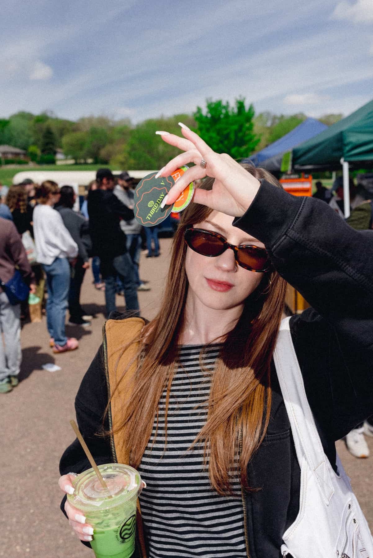 Girl in sunglasses holding up stickers.