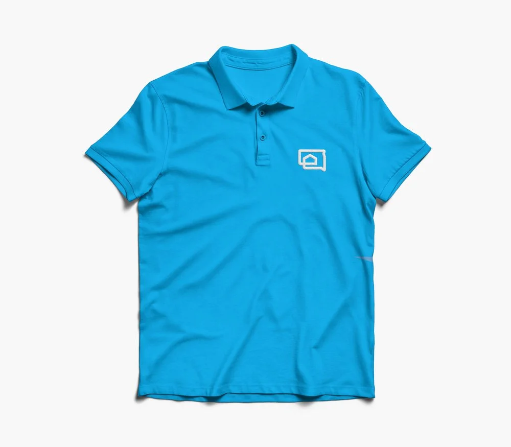SD Housing brand logo mark developed by The Sampson House embroidered on cyan blue polo.
