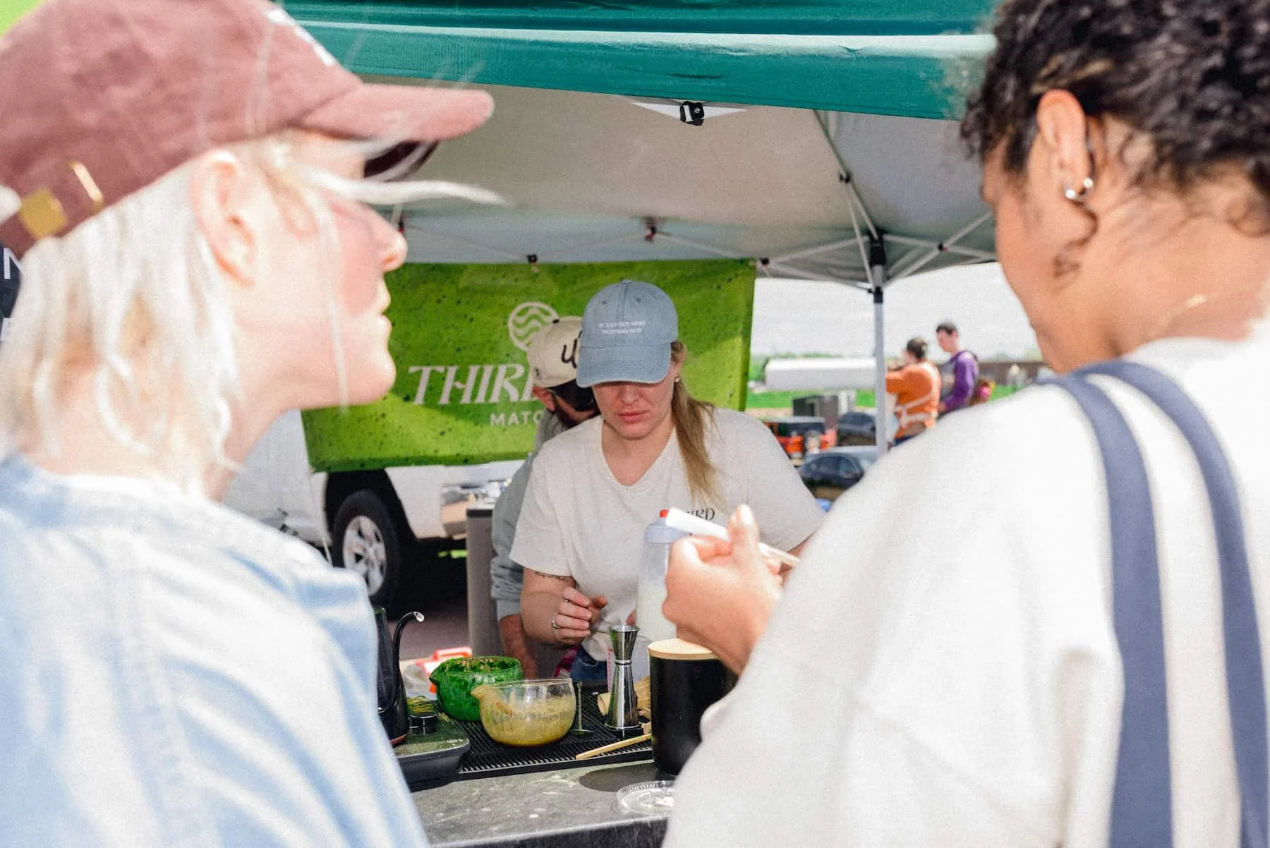 Two women watching lady make matcha.