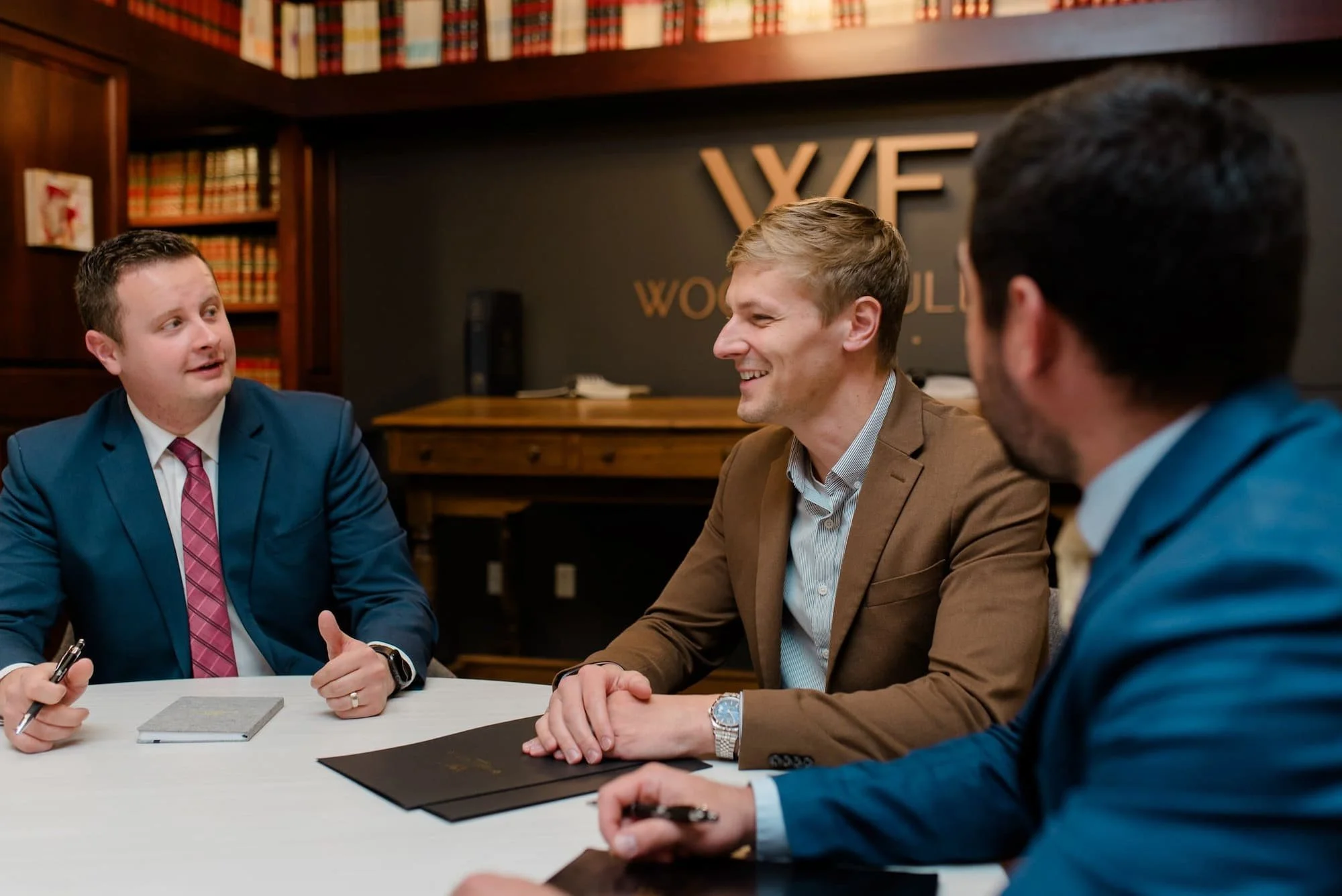 three Woods Fuller attorneys talking at table.
