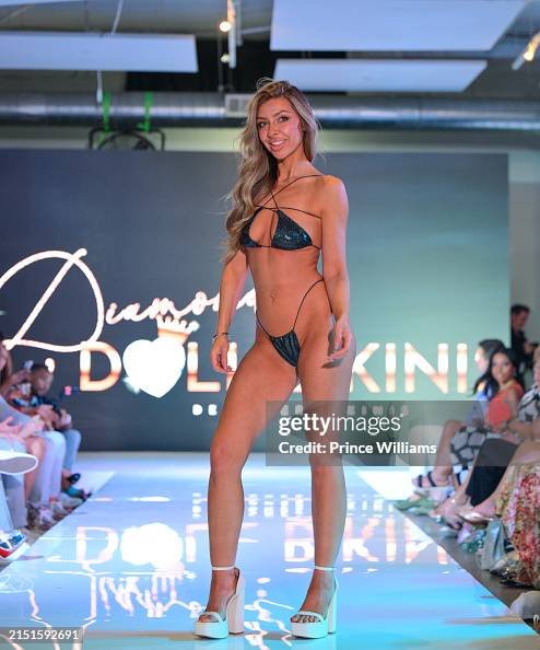 Female model walking on runway in bikini at fashion show, audience seated on sides