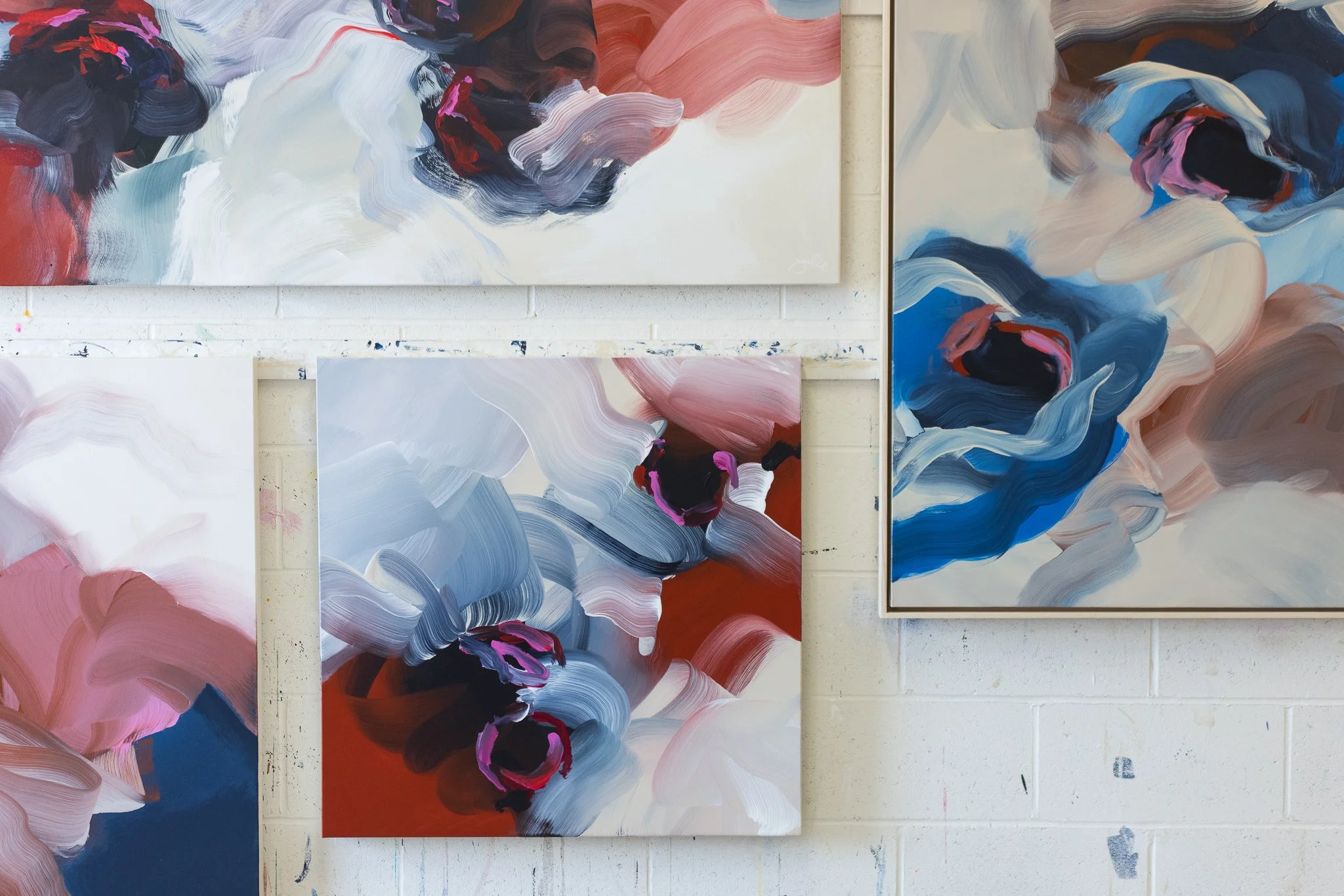 Bloom collection of abstract paintings on studio wall.