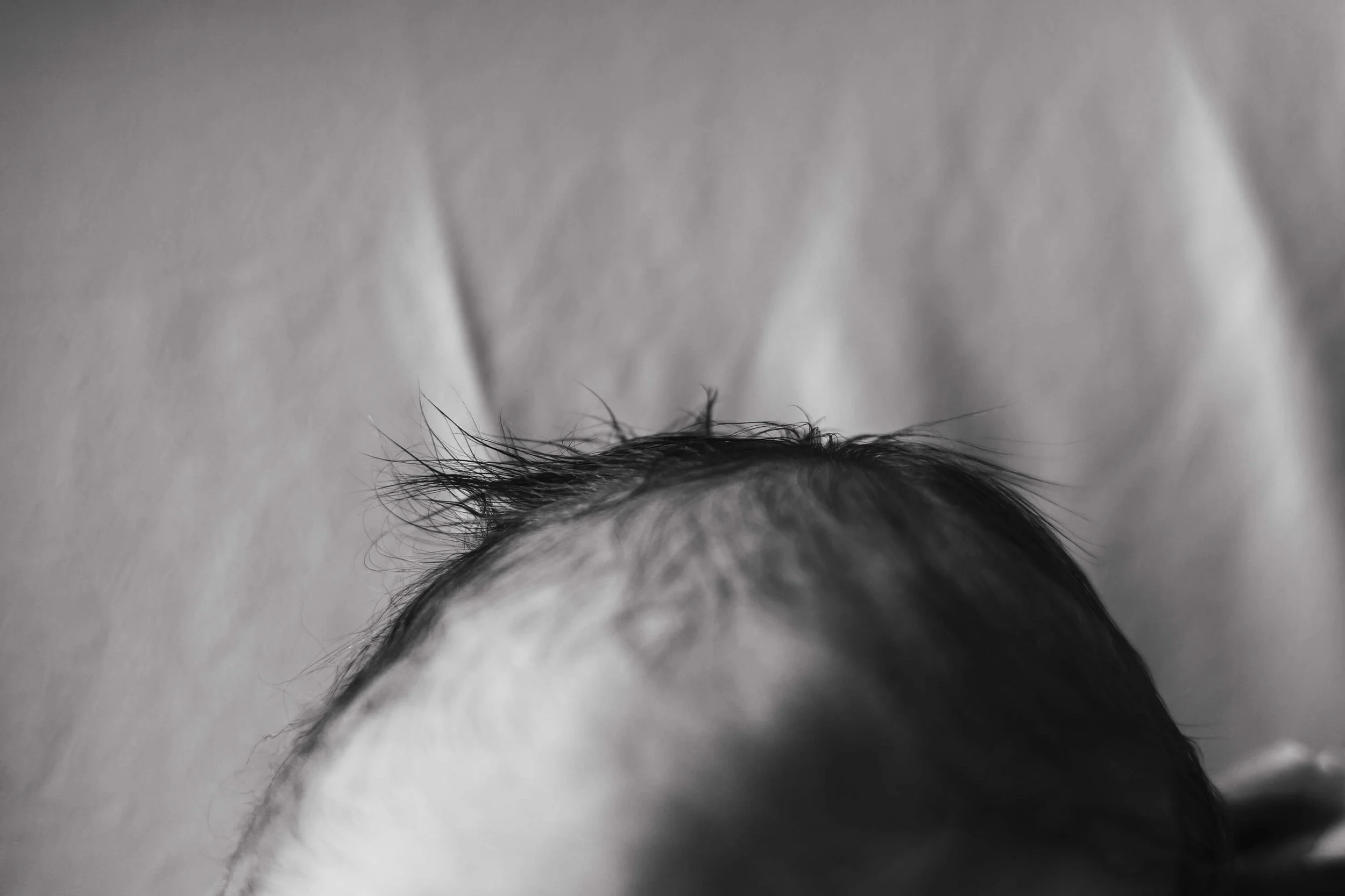 A black and white close up of newborn baby hair